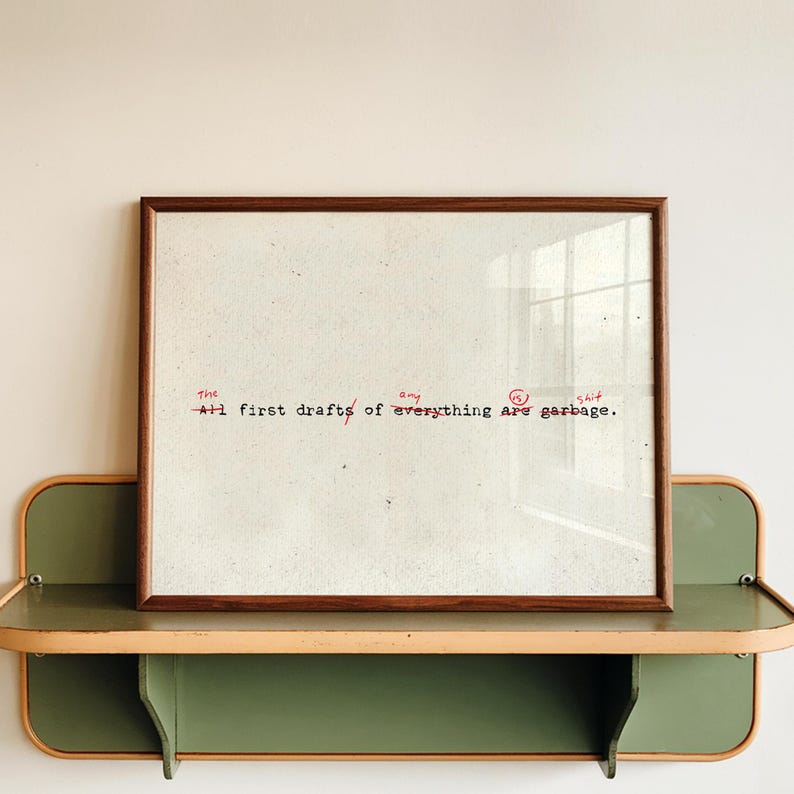 Puede incluir: Una impresi&oacute;n enmarcada con un marco de madera marr&oacute;n. La impresi&oacute;n tiene un fondo blanco con texto rojo que dice "The All first drafts of everything are garbage."
