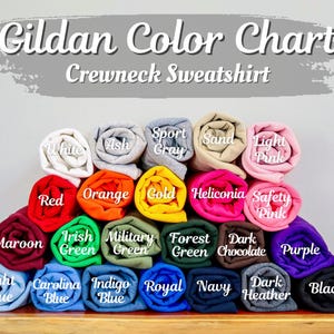 Puede incluir: Una carta de colores Gildan para sudaderas de cuello redondo con veinticinco muestras de tela enrolladas en varios colores, incluyendo blanco, ceniza, gris deportivo, arena, rosa claro, rojo, naranja, oro, heliconia, rosa ne&oacute;n, granate, verde y azul.