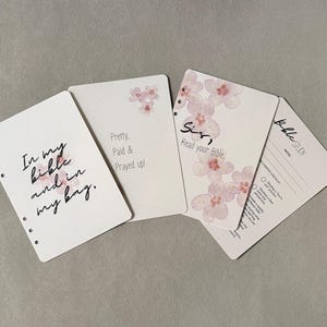 May include: Four white cards with floral accents and text. One card reads "In my bible and in my bag." Another says "Pretty, Paid & Prayed up!" A third card reads "Sis, Read your Bible." The fourth card is a Bible study checklist.