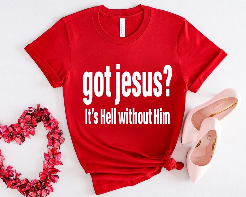 A red t-shirt with the text "got jesus? It's Hell without Him" printed on it, along with a pair of pink high heels and a heart-shaped arrangement of red flowers.