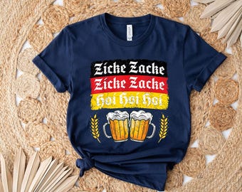 May include: Navy blue t-shirt with a graphic featuring the German flag colors and the words "Zicke Zacke hoi hoi hoi." Two beer mugs and wheat stalks are also included in the design.