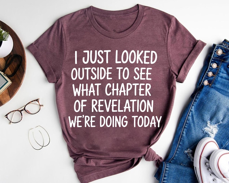 a purple t-shirt with white text, a pair of blue jeans, a pair of glasses, and a pair of white sneakers, all laid out on a white background.