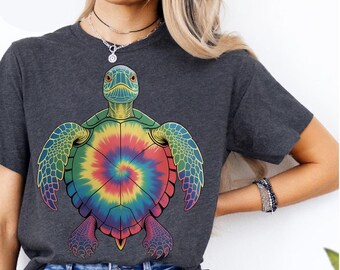 May include: Dark gray t-shirt featuring a colorful tie-dye sea turtle design. The turtle has a green head and flippers, with a shell in shades of red, yellow, blue, and green. The shirt is a casual style.