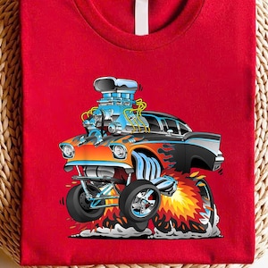 May include: Red t-shirt featuring a cartoon hot rod car with a large engine. The car is orange and black with flames, and the engine is blue. The car is depicted with large wheels and is emitting flames and smoke.