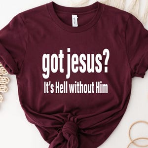 A burgundy t-shirt with the text "got jesus? It's Hell without Him" printed on it.