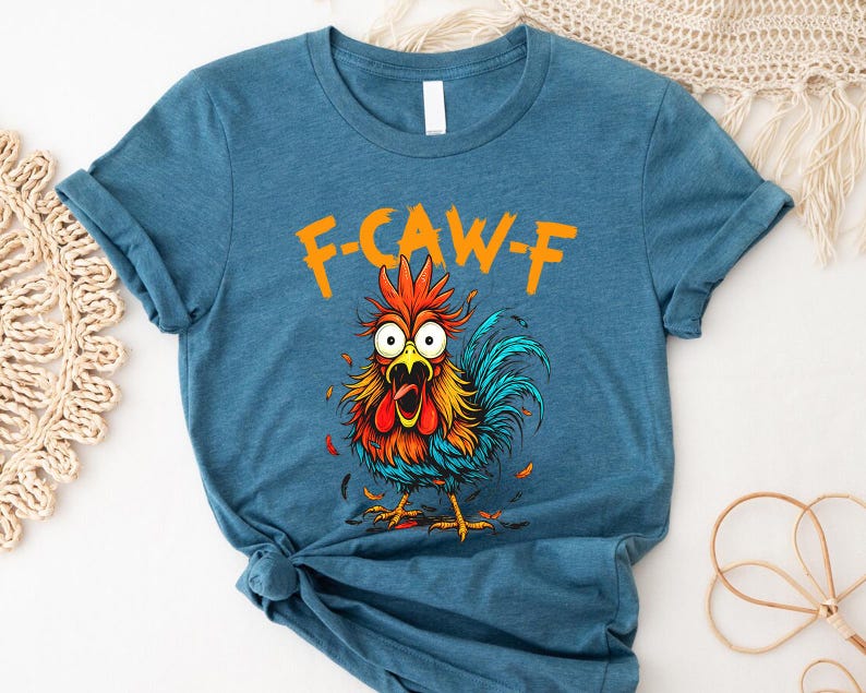 A blue t-shirt with a colorful cartoon rooster graphic and the text "F-CAWF" printed on it.