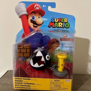 Może przedstawiać: Zestaw figurek Super Mario z Mario, Chain Chompem i blokiem z cegieł. Opakowanie zawiera logo Super Mario i napis "Chain Chomp with Block". Zalecane dla dzieci w wieku od 3 lat.