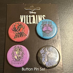 K&ouml;nnte beinhalten: Ein Disney Villains Button-Pin-Set. Das Set enth&auml;lt vier runde Pins mit Bildern von Disney-B&ouml;sewichten. Die Pins sind rot, blau, lila und schwarz. Der Text "Button Pin Set" befindet sich am unteren Rand der Karte.