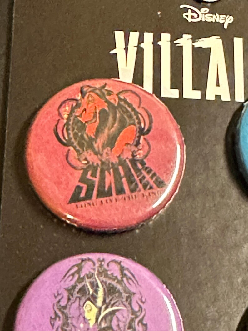 K&ouml;nnte beinhalten: Ein runder, roter Button mit einer Grafik von Scar aus Disneys Der K&ouml;nig der L&ouml;wen. Der Button hat das Wort "SCAR" in schwarzer Schrift, mit dem Satz "LONG LIVE THE KING" darunter. Das Disney Villains Logo ist sichtbar.