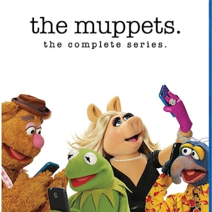 May include: A Blu-ray disc case for The Muppets: The Complete Series. The cover features Fozzie Bear, Kermit the Frog, Miss Piggy, and Gonzo, each holding a smartphone. The title text reads the muppets. the complete series. in black font.