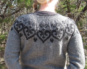 May include: A gray knitted sweater with a black and gray patterned design. The sweater has long sleeves and a crew neck.