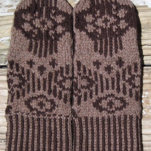 Puede incluir: Un par de guantes de punto marrones y negros con un patrón geométrico. Los guantes tienen un puño a rayas.