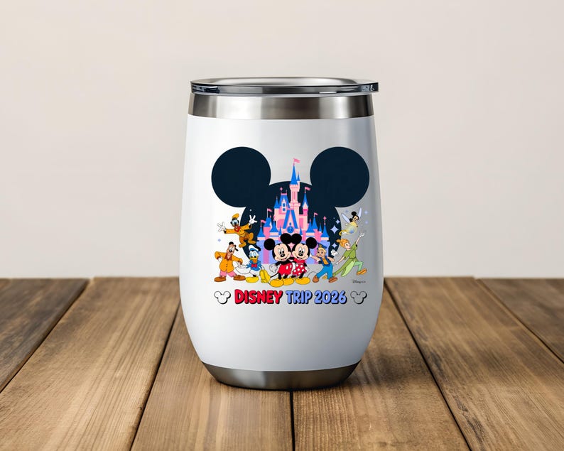 May include: White insulated tumbler with a silver rim and base. The tumbler features a black Mickey Mouse silhouette with a castle and Disney characters. The text "Disney Trip 2023" is printed in red and blue.