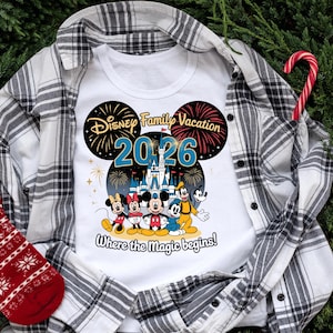 May include: White t-shirt with a Disney Family Vacation 2026 graphic featuring Mickey, Minnie, Donald, Goofy, and Pluto in front of a castle. The shirt is layered over a black and white plaid shirt, with a red and white Christmas stocking and a candy cane.