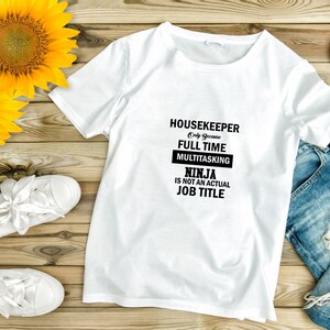 May include: White t-shirt with black text that reads "Housekeeper Only Because Full Time Multitasking Ninja Is Not An Actual Job Title"