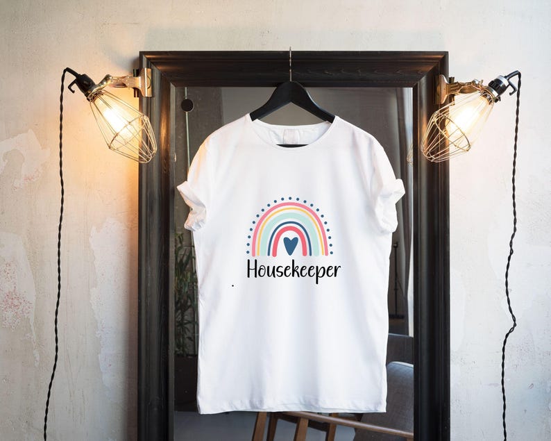 May include: White t-shirt with a rainbow and heart graphic and the text "Housekeeper".