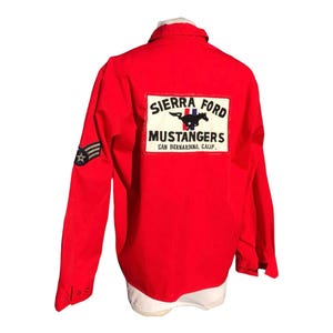 May include: Red long-sleeve shirt with a white patch on the back that says "Sierra Ford Mustangers San Bernardino, Calif.". The patch features a black and white horse with a red, white, and blue stripe.