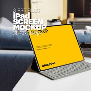 May include: A gray iPad with a yellow screen and a gray keyboard. The screen displays the text "tablet//iPad". The iPad is sitting on a white surface.