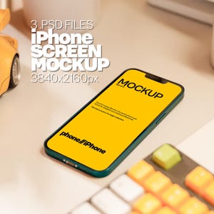May include: A green iPhone mockup with a yellow screen displaying the text "MOCKUP" and "phone//iPhone". The screen is surrounded by a black border. The phone is lying on a white surface.
