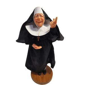 May include: A white ceramic mug with a black handle and the text "But First, Coffee" in a bold, black font. The mug is set against a neutral background, highlighting its simple design.