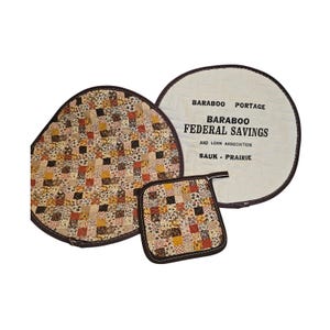 May include: A set of three quilted items: a half-circle mat, a round mat, and a square pot holder. The half-circle and square items feature a patchwork design in shades of brown, yellow, and red. The round mat has text that reads "Baraboo Federal Savings".