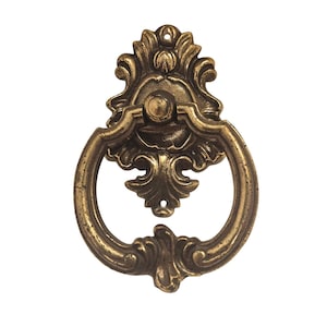 May include: Ornate antique brass drawer pull with a decorative backplate and a circular handle. The hardware features detailed floral and scrollwork designs, adding a vintage touch. The pull is designed for easy installation and is ideal for cabinets and drawers.