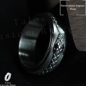 Op de afbeelding: Een zwarte onyx ring met een zilveren band met een gedetailleerd slangendesign. De ring is gegraveerd met de woorden "Talos Custom Rings".