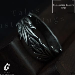 May include: A silver-colored ring with a leaf design. The ring features a detailed pattern of leaves wrapping around the band. The text "Personalized Engrave Rings" is visible in the upper right corner. The brand name "Talos Custom Rings" is also visible.