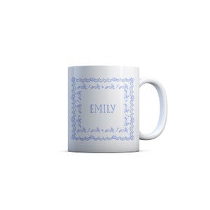 Puede incluir: Taza de cer&aacute;mica blanca con un borde azul con un patr&oacute;n repetido de conejos. El nombre "EMILY" est&aacute; impreso en el centro de la taza.