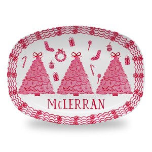 May include: White oval serving platter with a pink and white Christmas tree design. The platter has a scalloped edge and the words "McLerran" are printed in the center.