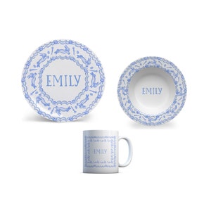 Puede incluir: Un juego de vajilla de cer&aacute;mica blanca con un patr&oacute;n de conejo azul y el nombre "Emily" en cada pieza. El juego incluye un plato, un taz&oacute;n y una taza.