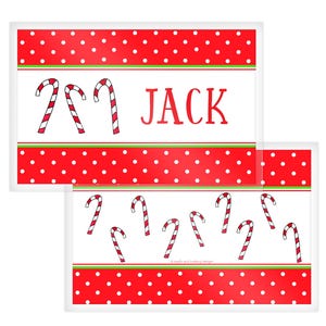 May include: Two rectangular Christmas-themed placemats. The top placemat has a red polka dot border, white center with two candy canes, and the name "JACK". The bottom placemat has multiple candy canes.