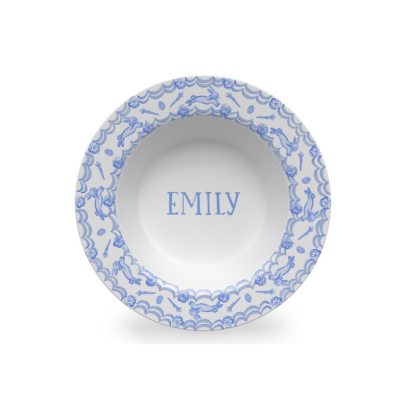 Puede incluir: Un taz&oacute;n de cer&aacute;mica blanco con un patr&oacute;n de conejo azul y blanco alrededor del borde. El taz&oacute;n tiene el nombre "EMILY" escrito en azul en el centro.