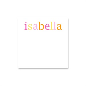 May include: A white square notepad with the name "isabella" printed in colorful letters. The letters are pink, yellow, orange, and a lighter pink. The notepad is on a white background.