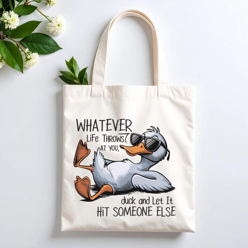 May include: Cream-colored tote bag featuring a cartoon duck wearing sunglasses, reclining with its feet up. The text reads "Whatever life throws at you, duck and let it hit someone else."
