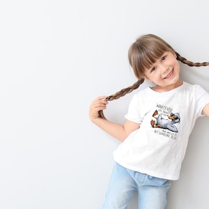 May include: White t-shirt featuring a cartoon duck wearing sunglasses and the text "WHATEVER Life Throws at You, Duck and Let It Hit Someone Else." The duck is lying down with its feet up. The shirt is worn by a young person.