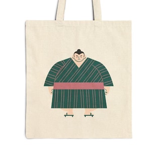 May include: A cream tote bag with a cartoon illustration of a sumo wrestler. The wrestler is depicted in a green and pink striped outfit. The design is minimalist, with a clear outline of the wrestler's features.