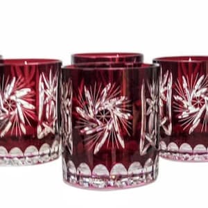 May include: Set of six ruby red crystal glasses. Each glass features a starburst design and a scalloped base. The glasses are cylindrical and appear to be made of cut crystal.