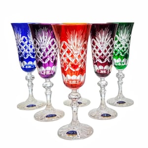 Può includere: Set di sei flûte da champagne in cristallo colorato. Ogni bicchiere presenta un colore diverso: blu, viola, rosso, bordeaux e verde. I bicchieri di cristallo hanno un motivo intagliato e un gambo trasparente.