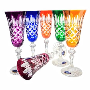 Può includere: Un set di sei flûte da champagne in cristallo colorato. I bicchieri sono nei toni del viola, blu, arancione, verde e giallo. Ogni flûte presenta un motivo a taglio diamante e un gambo e una base trasparenti.