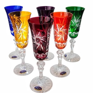 Può includere: Set di sei flûte da champagne in cristallo colorato. Ogni flûte presenta un colore diverso: blu, giallo, viola, rosso, arancione e verde. I bicchieri di cristallo hanno un design inciso dettagliato e poggiano su una base trasparente e decorativa.