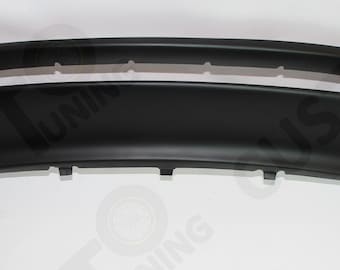 May include: A black plastic car bumper with a cutout for a license plate. The bumper has a smooth, rounded design.