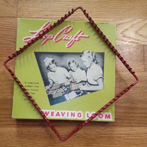 May include: A square red metal weaving loom frame with evenly spaced pegs positioned over a vintage Loop Craft box. The box features a light green background, a black and white photograph of three children weaving, and the text Loop Craft.