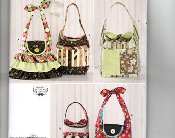 May include: A Simplicity sewing pattern envelope 2169 for one size bags. The front displays four different handbag designs featuring various fabric patterns, including polka dots, floral prints, stripes, and ruffles, with a barcode and text.