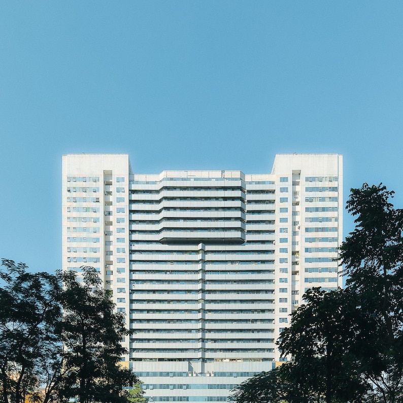 May include: A large, white, modern office building with many windows. The building is surrounded by trees.
