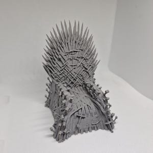 Könnte beinhalten: Ein graues 3D-gedrucktes Modell des Eisernen Throns aus der Fernsehserie Game of Thrones. Der Thron besteht aus Schwertern und ist ein beliebtes Sammlerstück für Fans der Serie.