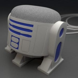 Op de afbeelding: Een witte en blauwe Google Home slimme speaker met een R2-D2-thema en een grijze stoffen bovenkant.