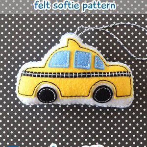 Puede incluir: Un patrón de taxi amarillo de fieltro NYC con ruedas negras y una ventana azul. El softie tiene una cuerda para colgar. El texto "beep beep!" está escrito en azul debajo del softie. El texto "trellis & thyme" está escrito en azul en un círculo debajo del texto.