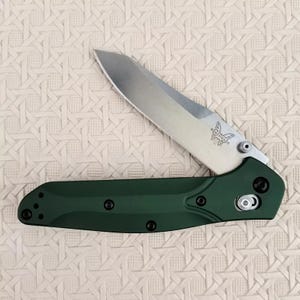 May include: A green folding knife with a silver blade and a butterfly logo. The knife is open and the blade is partially extended.