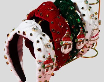 Op de afbeelding: Vier kerstthema hoofdbanden met sneeuwpopversieringen. De hoofdbanden zijn gemaakt van fluweel in rood, groen en wit en zijn versierd met strass.